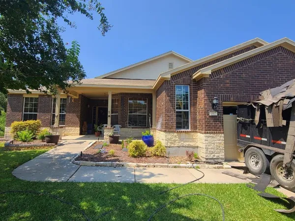 Brick ranch home with dump trailer on site